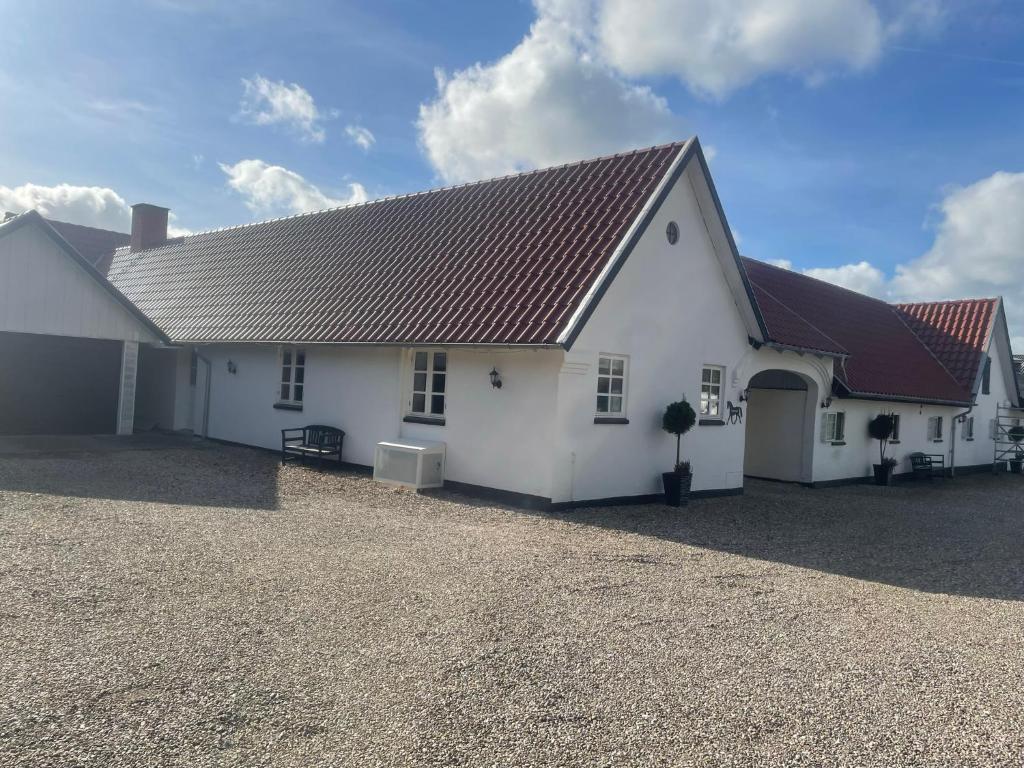 uma casa branca com um telhado castanho e uma entrada em Dejlig lejlighed em Svinninge
