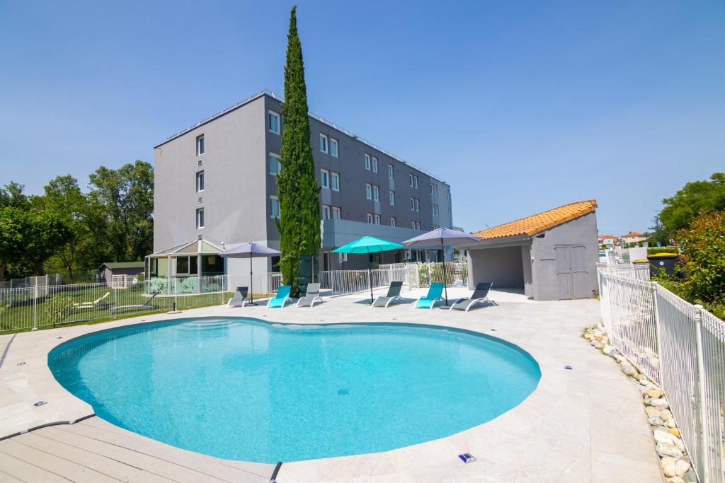 a swimming pool with chairs and a building at Kyriad Direct - Bourg les Valence in Bourg-lès-Valence