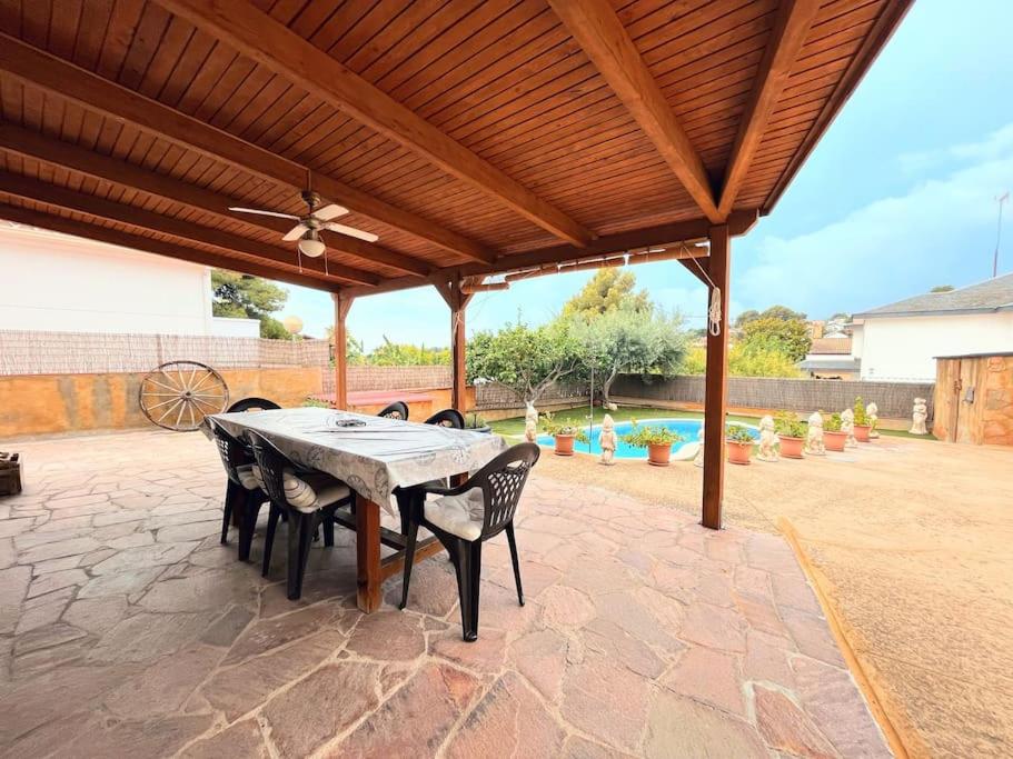 un patio con mesa y sillas bajo un pabellón en Casa de vacaciones en castelldefels ¡tranquilidad y piscina!, en Castelldefels