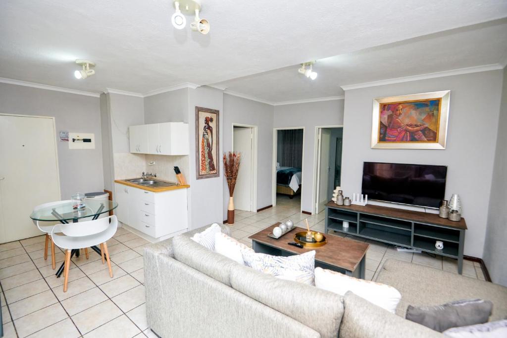 a living room with a couch and a tv at Cosy Hatfield Apartment in Pretoria