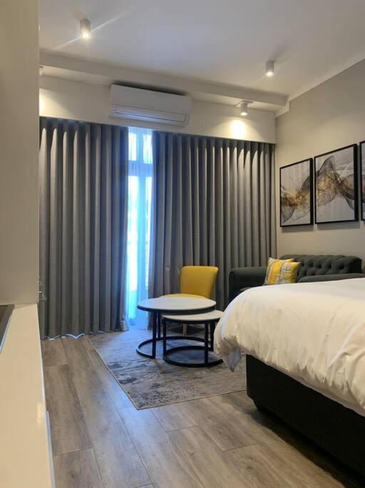 Pretoria的住宿－Entire Studio Apartment @MenlynMaine，一间卧室配有一张床、一张桌子和一张沙发