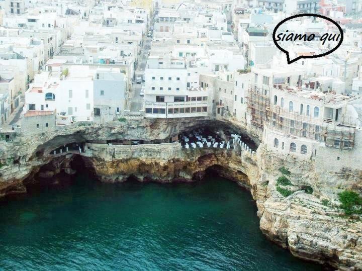 eine Gruppe von Menschen, die auf einer Brücke über das Wasser stehen in der Unterkunft Tra le Mura in Polignano a Mare