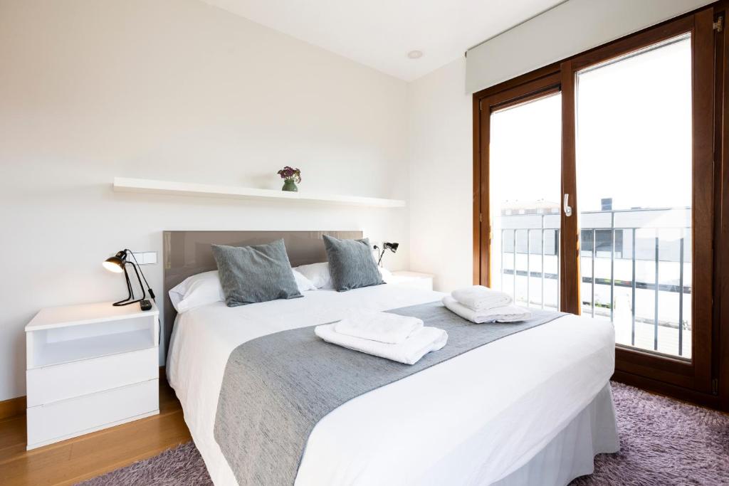 een witte slaapkamer met een groot bed en een raam bij Jaizkibel by Basquelidays in Hondarribia