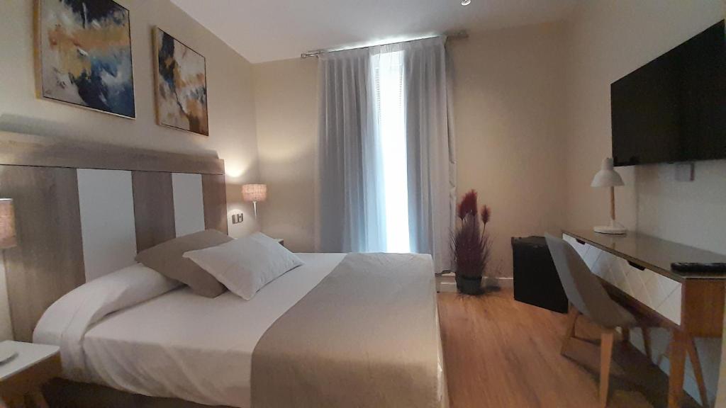 a bedroom with a bed and a desk and a window at Olivae Hostal Boutique in Cáceres