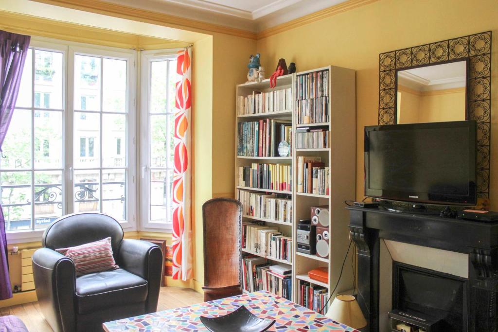 d'un salon avec une cheminée, une télévision et des étagères de livres. dans l'établissement Cozy love nest near Stade de France, à Paris
