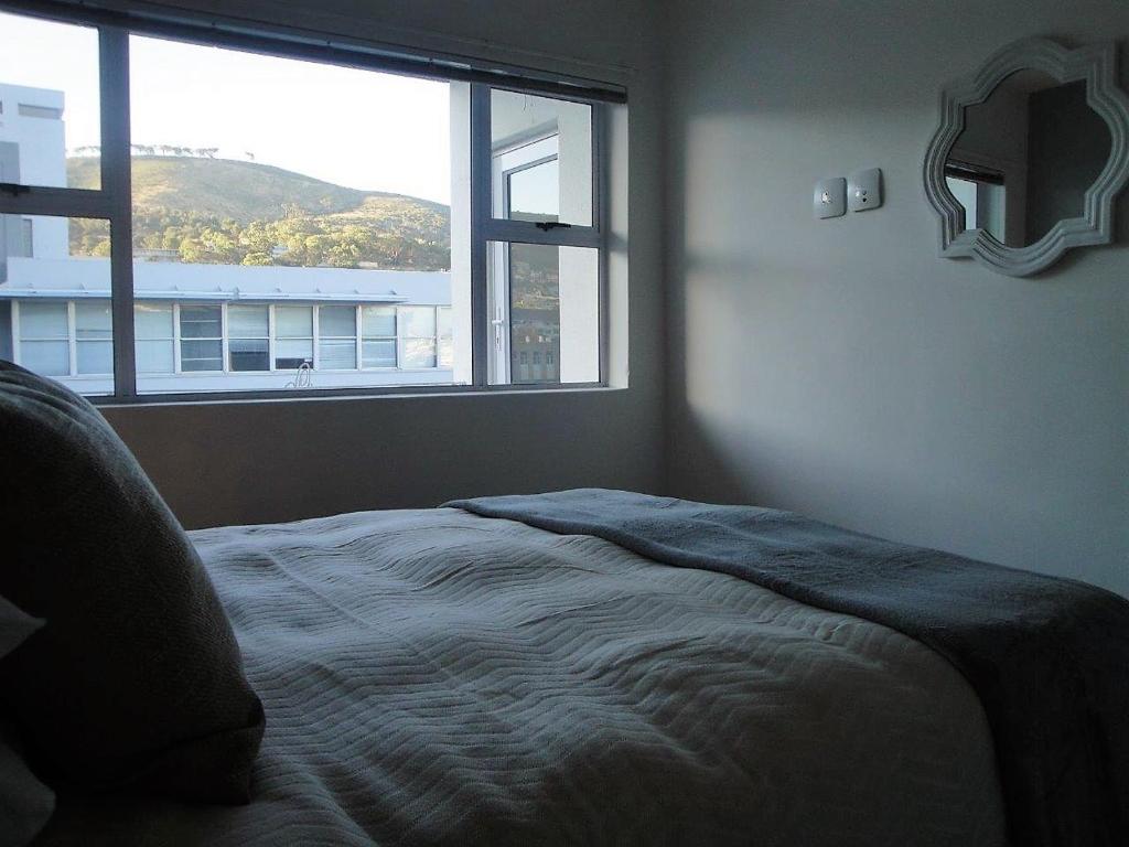 1 dormitorio con cama y ventana grande en Overbeek 1 Bedroom 702 Apartment on Kloof Street, en Ciudad del Cabo