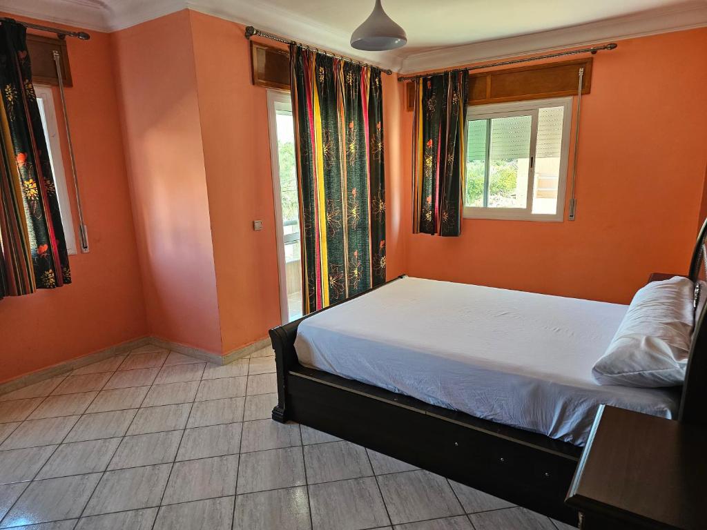 Schlafzimmer mit orangefarbenen Wänden, einem Bett und einem Fenster in der Unterkunft Résidence Anouar in Tétouan