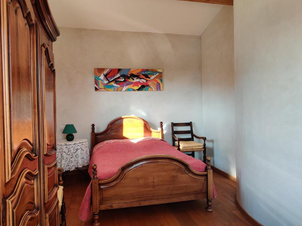 a bedroom with a wooden bed and a painting on the wall at LE CHARME DU VENTOUX in Crillon-le-Brave