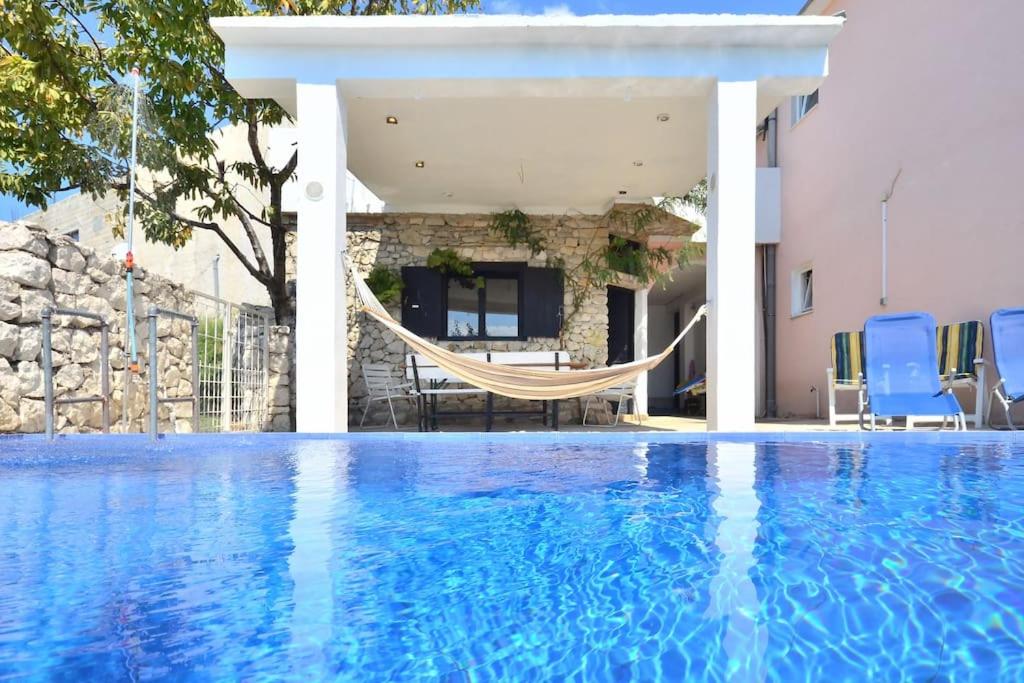 uma piscina com rede em frente a uma casa em Kuća za odmor u blizini Splita em Jesenice