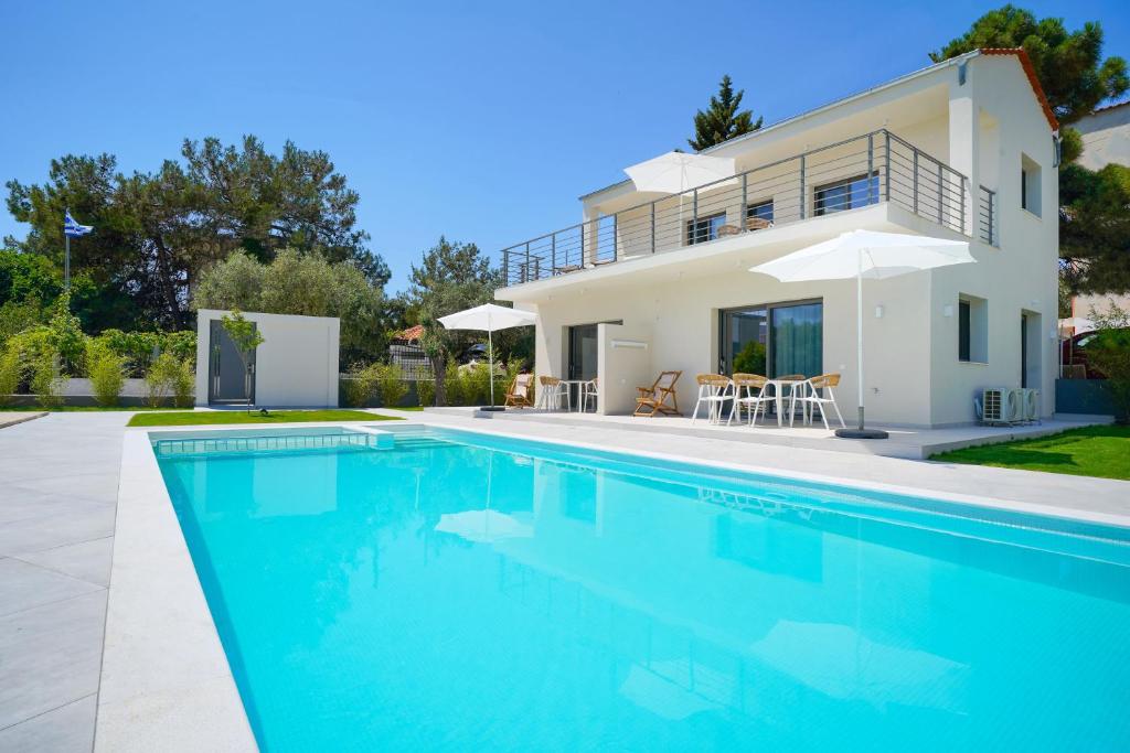 a villa with a swimming pool and a house at Filoxenia Luxury Apartments in Potos