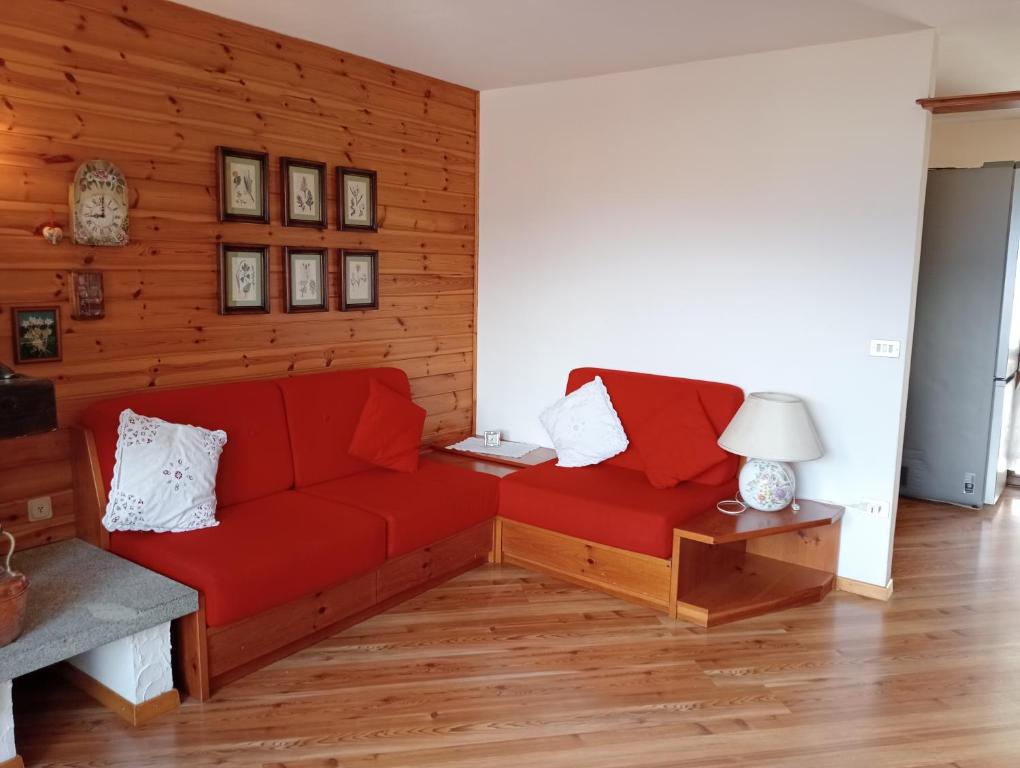 sala de estar con sofá rojo y mesa en La finestra sulle Dolomiti, en Carano