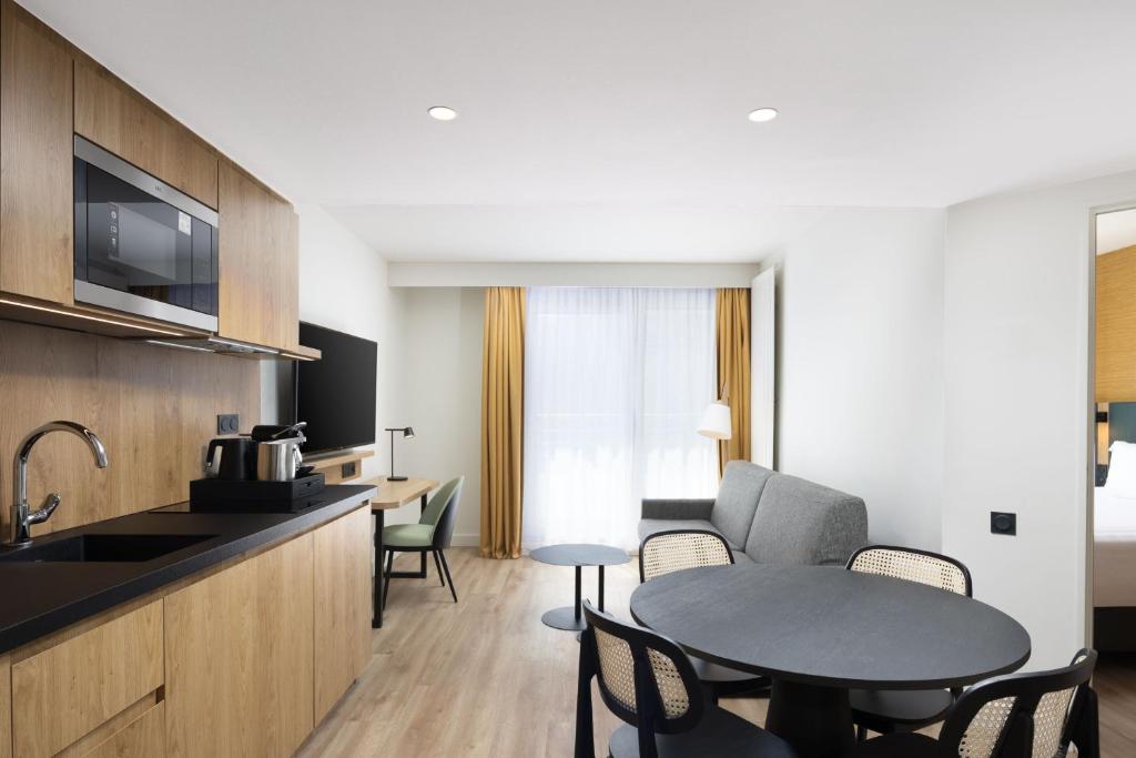 Cette chambre comprend une cuisine et une table avec des chaises. dans l'établissement Residence Inn by Marriott Paris Didot Montparnasse, à Paris