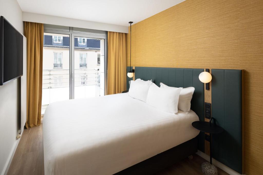 a bedroom with a large bed and a large window at Residence Inn by Marriott Paris Didot Montparnasse in Paris