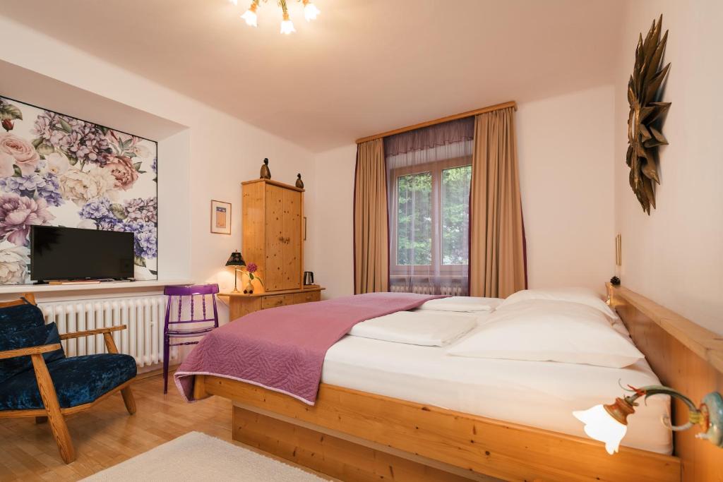 a bedroom with a large bed and a tv at Villa Marwa - eine Ruheoase im Grünen in Innsbruck