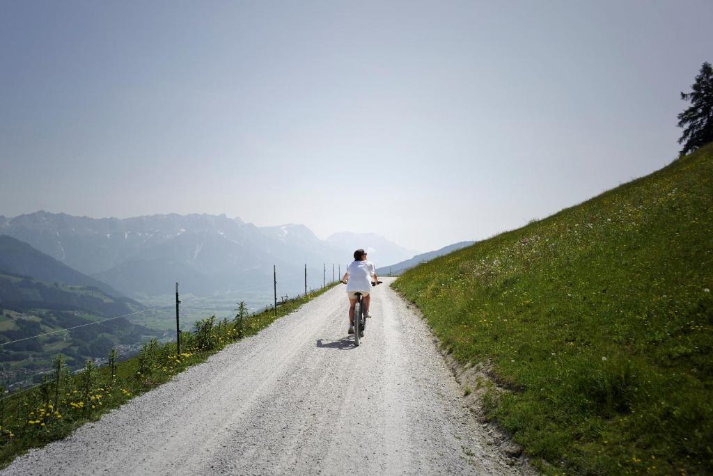 a person riding a bike down a dirt road at Holzhotel Forsthofalm in Leogang