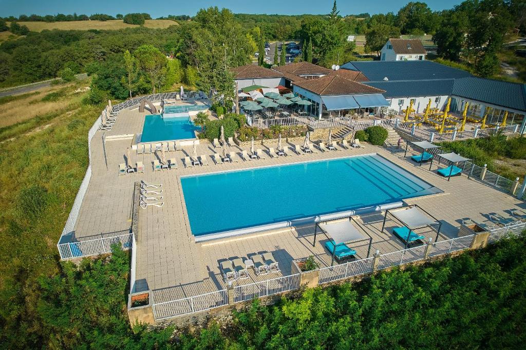 - une vue sur la piscine bordée de chaises et de parasols dans l'établissement Domaine de Lanzac, à Lanzac