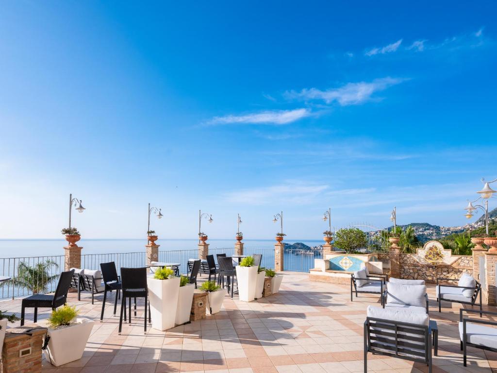 a patio with chairs and tables and a view of the ocean at Hotel Olimpo le Terrazze in Letojanni