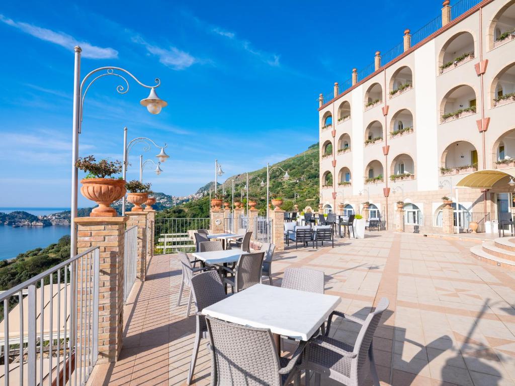 a balcony of a hotel with tables and chairs at Hotel Olimpo le Terrazze in Letojanni