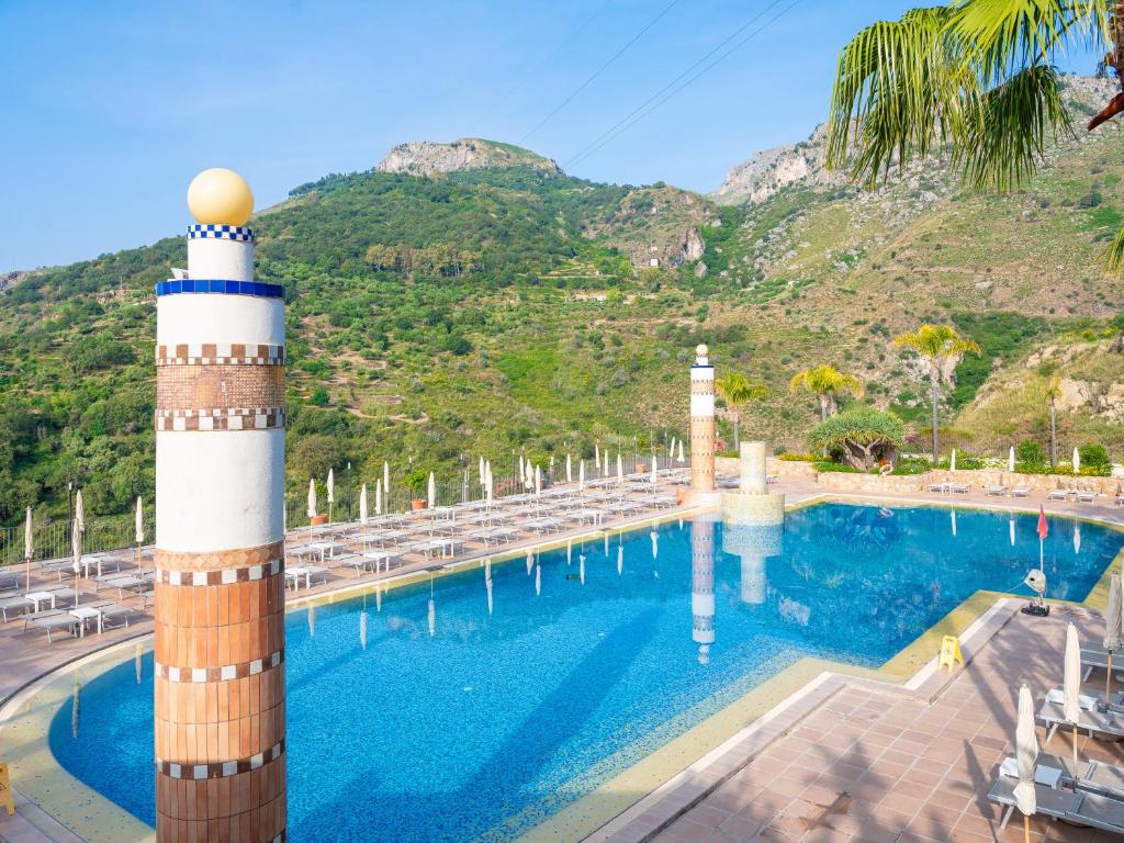 a pool with a lighthouse next to a mountain at Hotel Olimpo le Terrazze in Letojanni