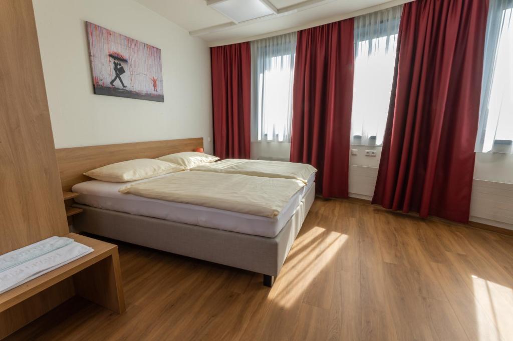 a bedroom with a bed and red curtains at Hotel Sommerhaus Linz in Linz