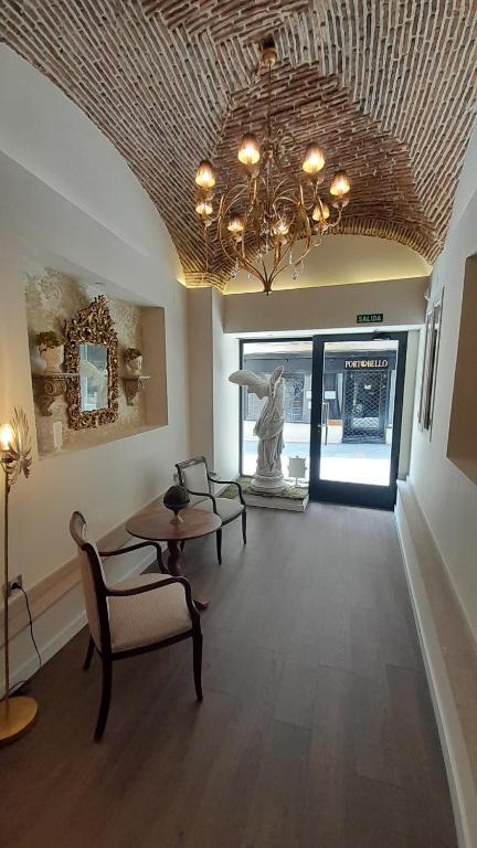 a living room with a chandelier and a table and chairs at Olivae Hostal Boutique in Cáceres