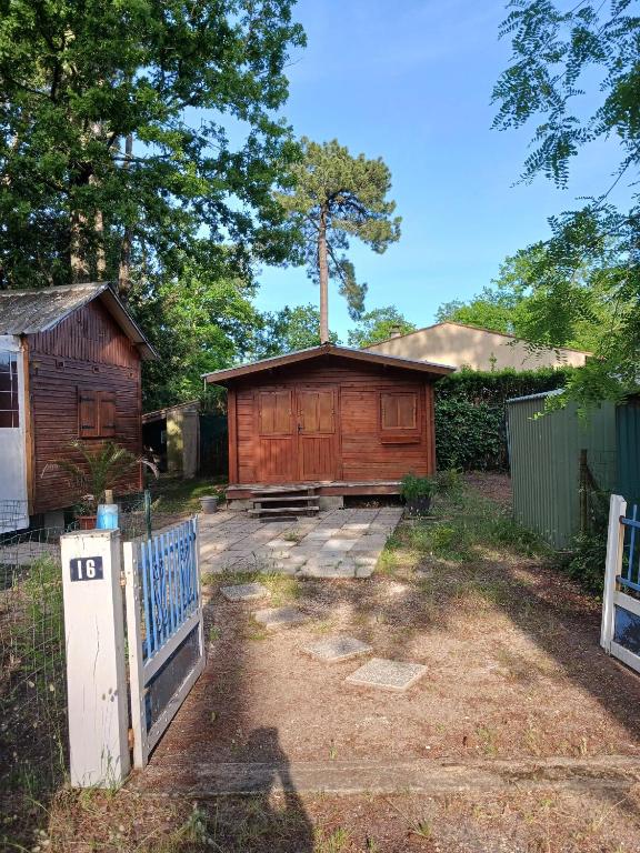 une maison en bois avec un portail et une clôture dans l'établissement MH 16 LA TREMBLADE, à La Tremblade