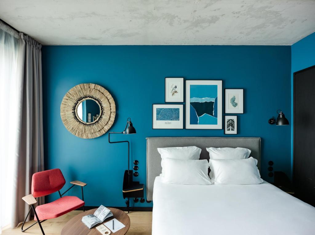 a blue bedroom with a bed and a red chair at Deskopolitan House in Paris