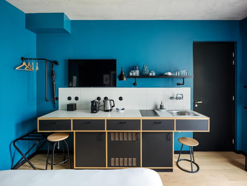 a kitchen with blue walls and a sink and stools at Deskopolitan House in Paris