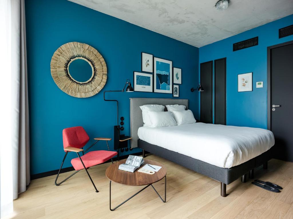 a blue bedroom with a bed and a red chair at Deskopolitan House in Paris