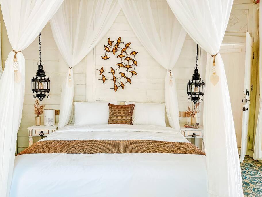 Schlafzimmer mit einem weißen Bett und weißen Vorhängen in der Unterkunft Mytongos Private Villa in Nusa Lembongan