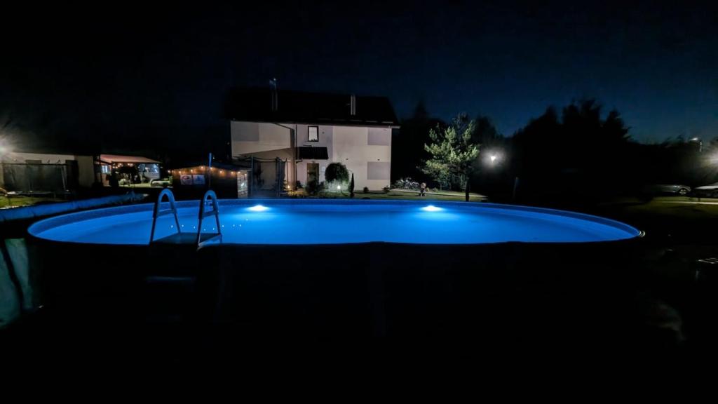 a swimming pool at night with a house in the background at Słoneczna Sarbinówka in Sarbinowo