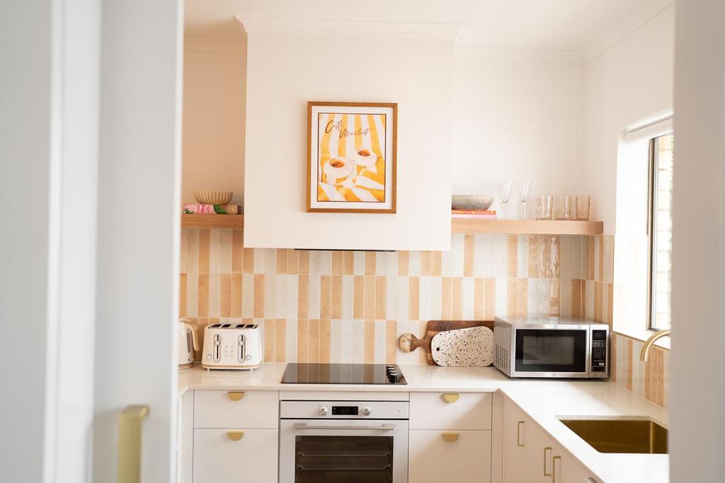 a kitchen with a stove and a microwave at Luxury hideaway holiday unit in CBD in Mount Gambier