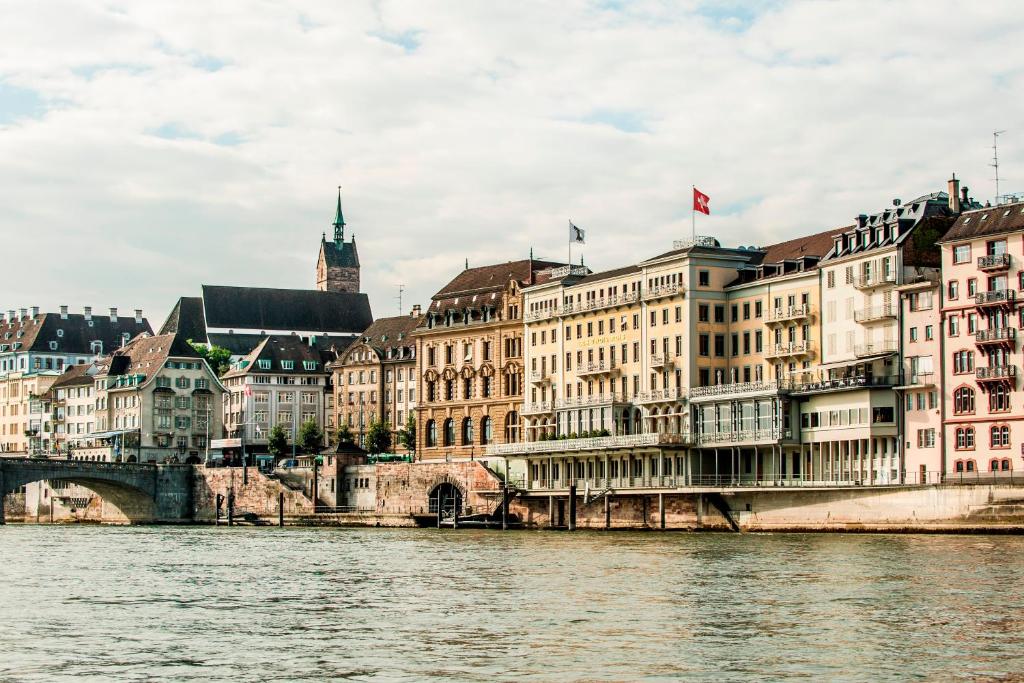 Blick auf einen Fluss mit Gebäuden und einer Brücke in der Unterkunft Grand Hotel LES TROIS ROIS in Basel