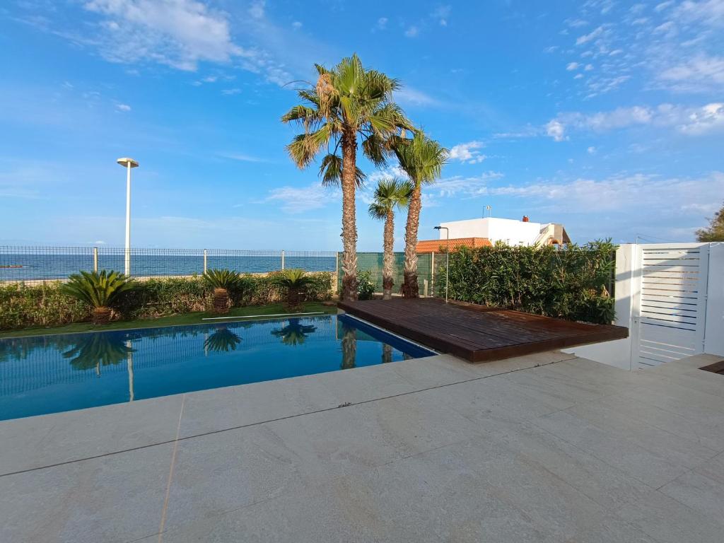una piscina con palmeras y el océano en Casa Del Mar, piscina privada frente al mar, en Cullera