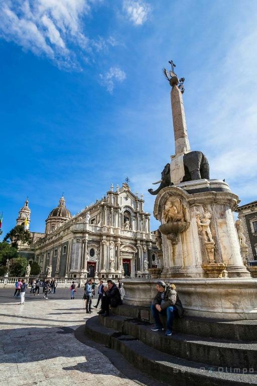 a group of people sitting around a fountain in front of a building at Casaurora Centro Storico in Catania