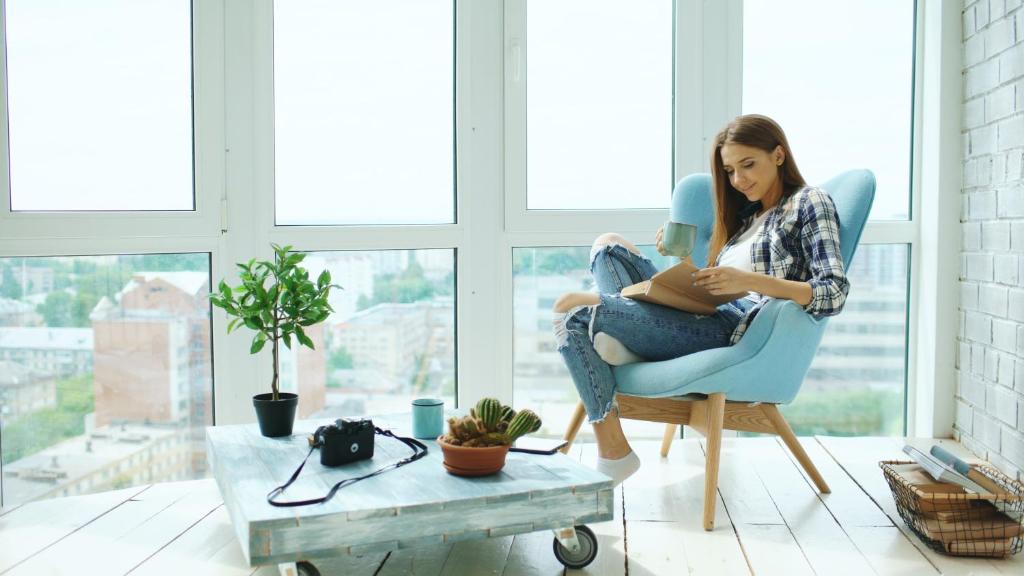 una mujer sentada en una silla leyendo un libro en Executive Apartment’s Mk, en Milton Keynes