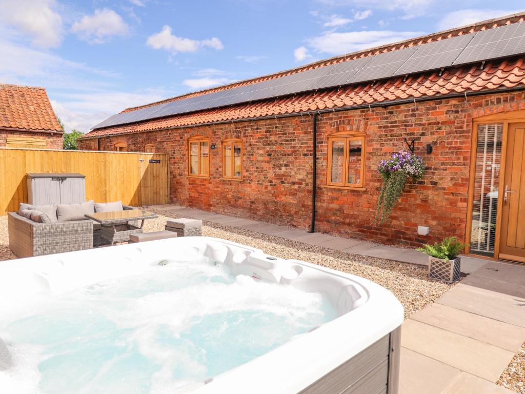 bañera de hidromasaje en un patio junto a un edificio de ladrillo en The Grange Cottage 1, en Grimsby