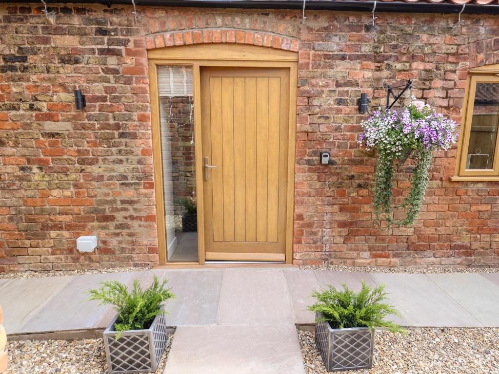 a wooden door on a brick building with two potted plants at The Grange Cottage 2 in Grimsby