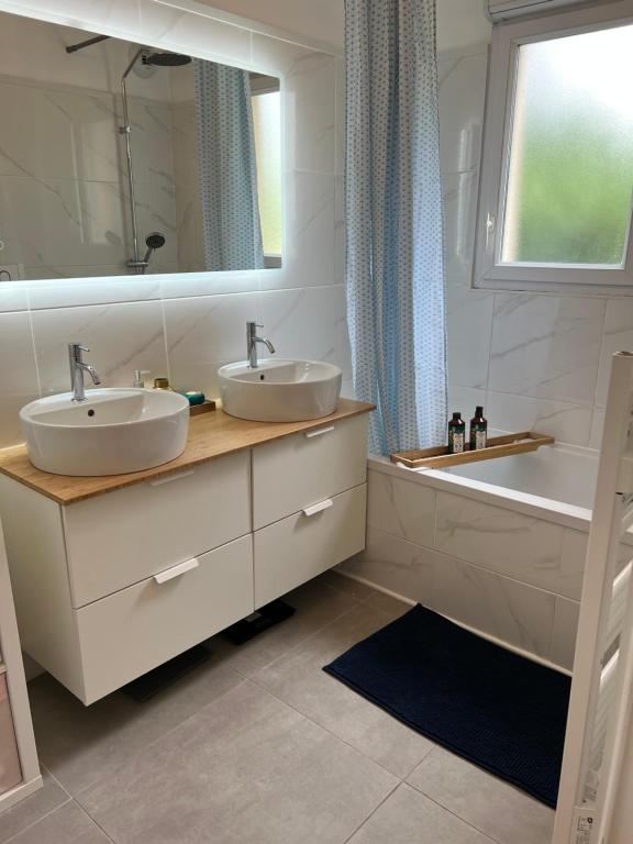 a bathroom with two sinks and a tub and a mirror at Appartement Disneyland Montevrain 77 in Montévrain