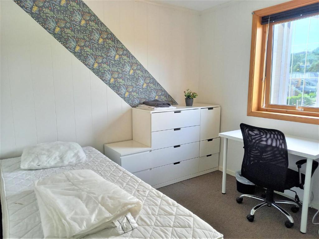 a bedroom with a bed and a desk and a window at Single room with shared spaces in Vennesla