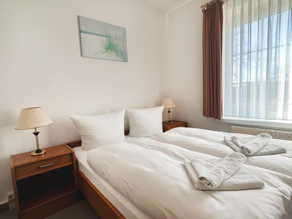 1 dormitorio con 2 camas con sábanas blancas y ventana en Pension Zur Inselbrücke en Wolgast