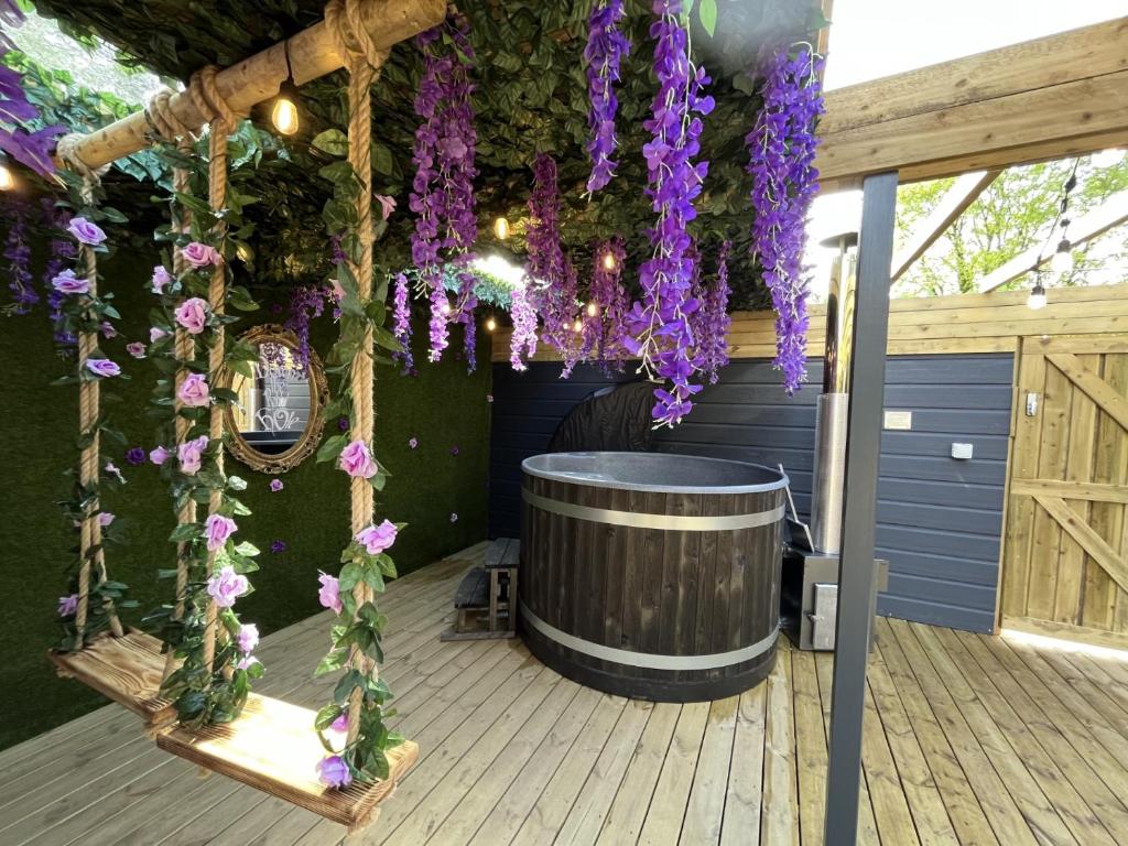 a covered deck with a barrel and purple flowers at Wonderland Retreats in Carnforth