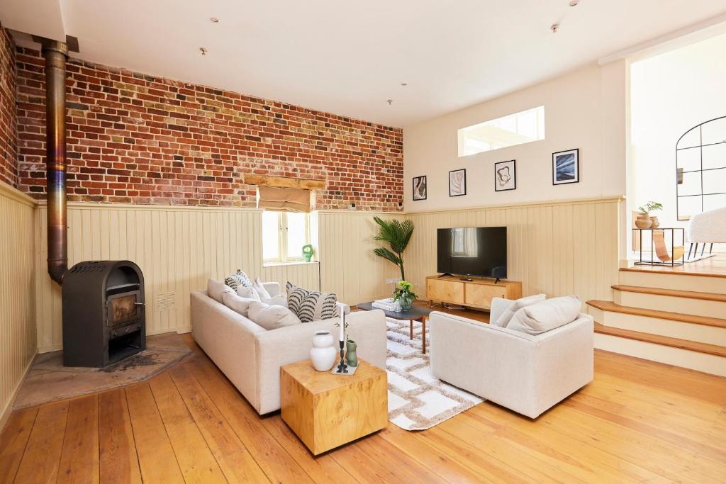un soggiorno con 2 divani e un muro di mattoni di The Chelmsford Hideaway - Spacious 5BDR House with Patio + Garden a Chelmsford