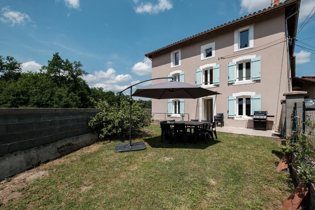 a table with an umbrella in front of a house at Le Verdier - Charmante maison pour 10 avec jardin in Peschadoires