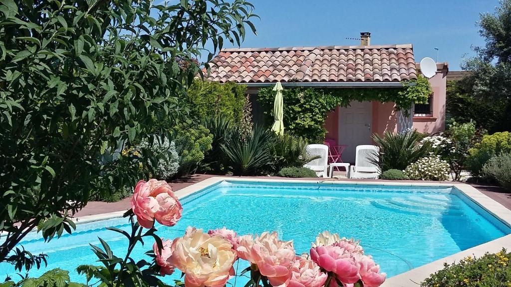 a swimming pool with flowers in front of a house at Les Cyprès Florentins in Colomiers