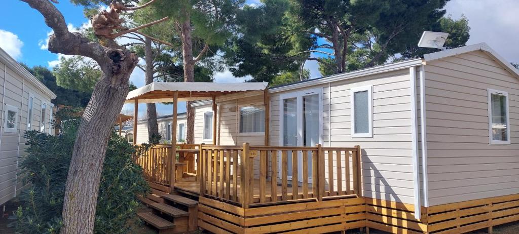 una casa pequeña con porche y terraza en Mobil Home (Clim, TV)- Camping Falaise Narbonne-Plage 4* - 003, en Narbonne-Plage