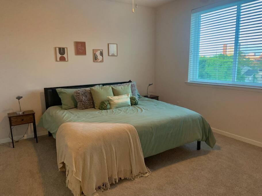 een slaapkamer met een bed met een raam en een nachtkastje bij Contemporary Cozy Apartment in Baltimore