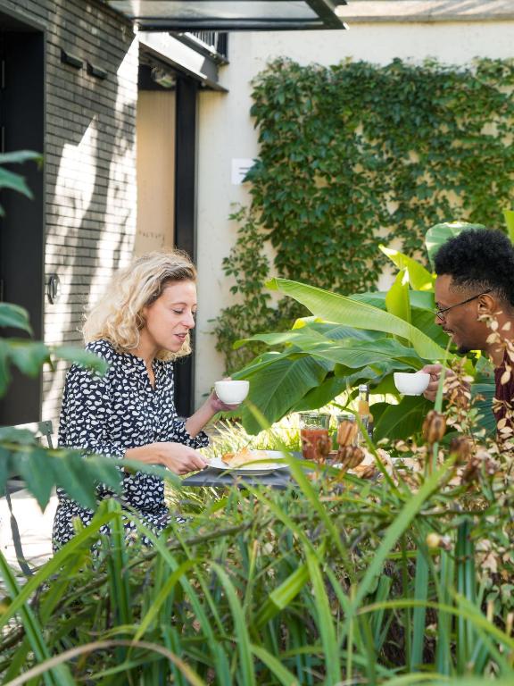 a woman sitting at a table in a garden at Deskopolitan House in Paris