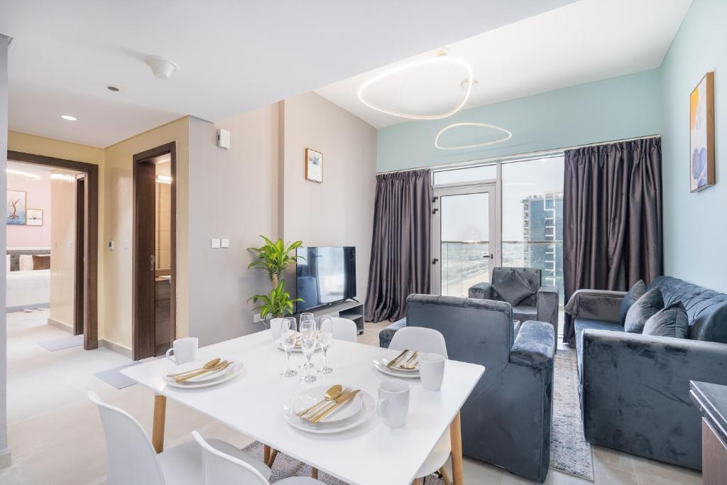 Trinity Holiday Homes - Spacious Modern Living 2BR Unique Apartment في دبي: غرفة معيشة مع طاولة وكراسي بيضاء