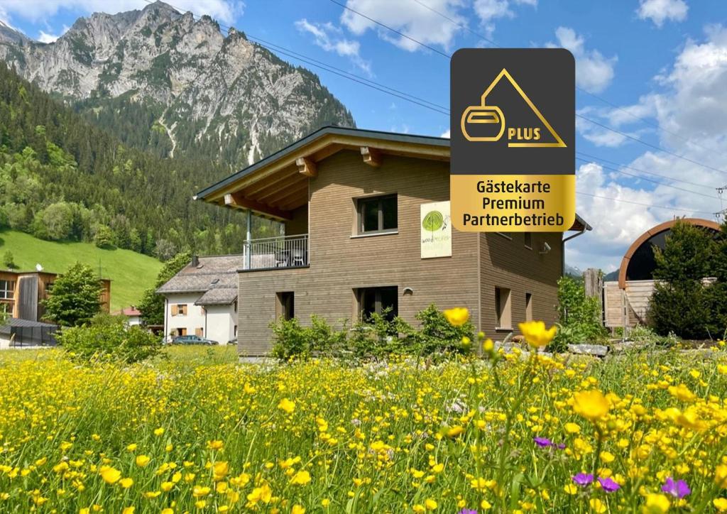 un bâtiment avec un panneau dans un champ de fleurs dans l'établissement Woodpecker Chalets, à Klösterle am Arlberg